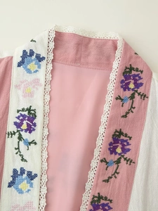 Dettaglio dello scollo con bordo in pizzo bianco e ricamo floreale su top di lino