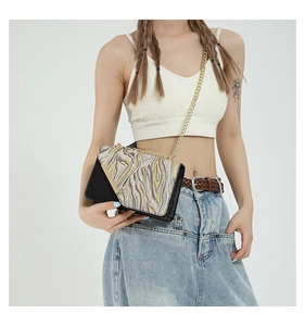 Detailed view of black flap crossbody bag with wavy embroidery and gold chain strap