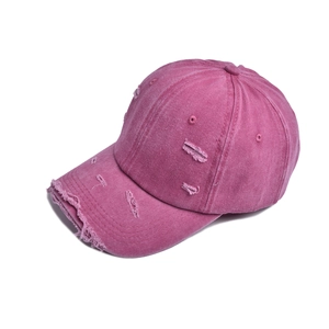 Close-up of distressed ripped edges on a vintage washed magenta cotton baseball cap
