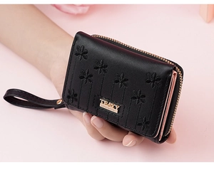 Detail of black PU leather wallet featuring floral embroidery and gold zipper closure