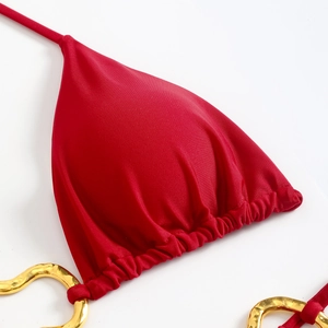 Close-up of red bikini top featuring glossy fabric and golden heart-shaped metal rings