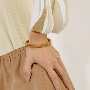 Detailed close-up of a gold-plated woven mesh bracelet on a model's wrist