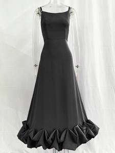 Detail of elegant black satin evening gown featuring ruffled hem and sleek strap design