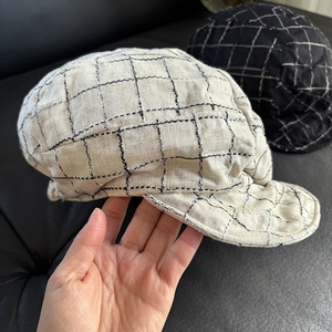 Detailed close-up of retro plaid linen newsboy caps in cream and black checkered fabric