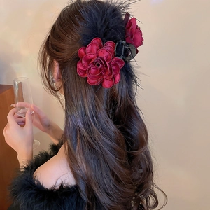 Detail of burgundy acrylic flower hair claw with feather tassels and crystal accents