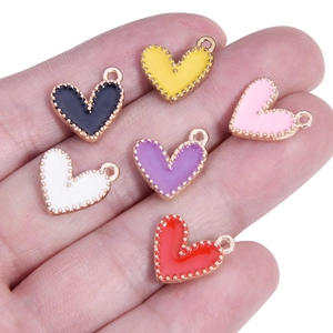 Detailed view of six colorful enamel heart pendants held in hand to show size and texture