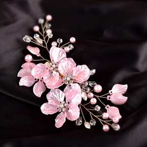 Detailed close-up of pink resin flowers with gold wire, crystals, and pearls on black silk