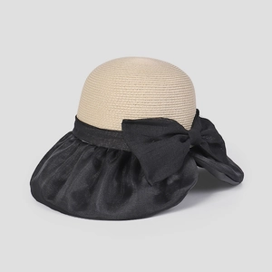 Dettaglio di elegante cappello da sole estivo in paglia con grande fiocco nero decorativo