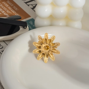 Detailed view of hollow camellia flower ring in 18K gold finish on a ceramic tray