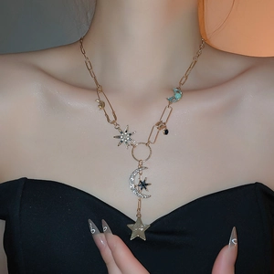 Détail du collier doré avec pendentifs étoile et lune sertis de cristaux sur mannequin