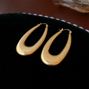 Macro view of polished gold U-shaped metal earrings on a black velvet display background