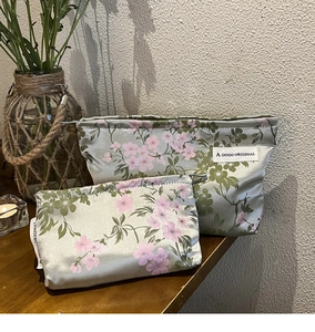 Detail of satin makeup bags with pink floral prints on a rustic wooden surface