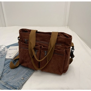 Detailed view of brown corduroy multi-pocket crossbody bag with canvas strap on bed