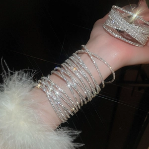 Close-up of layered silver bracelet featuring pearls, crystals and a delicate feather charm