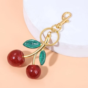 Detail of red glitter cherry keychain with green leaves and golden metal lobster clasp