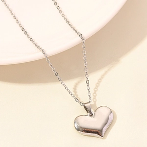 Macro view of a polished silver heart pendant necklace with a fine minimalist link chain