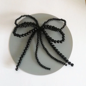 Detail einer eleganten schwarzen Perlen-Schleife mit Quasten zur Schuhdekoration