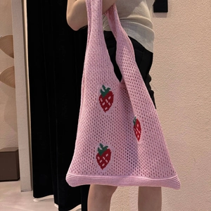 Detailed knit texture of a pink crochet tote bag featuring vibrant red strawberry patterns