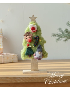 Close-up of handmade green wool felt Christmas tree with LED lights and deer decor