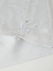 Dettaglio macro di paillettes d'argento e fodera bianca su abito da festa donna