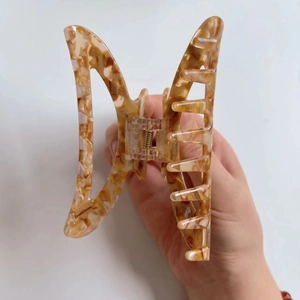 Detailed close-up of amber tortoiseshell large hair claw clip with golden metal spring