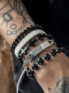 Close-up of men's layered beaded bracelets with a black cross and woven leather details