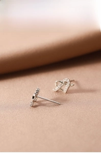 Detailed shot of S925 sterling silver heart earrings with white zircon on silk fabric