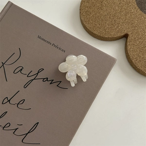 Dettaglio di un fermaglio per capelli a fiore perlato bianco su un libro vintage