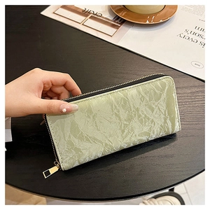 Macro shot of light green pleated leather wallet with gold zipper in a lifestyle setting