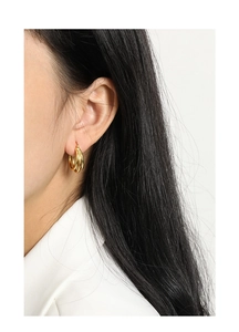 Macro detail of triple-layered gold hoop earrings showing polished metallic texture