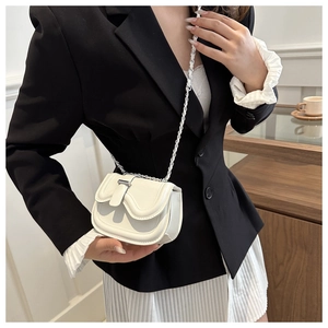 Close-up of white leather saddle bag featuring silver chain strap and metal clasp detail