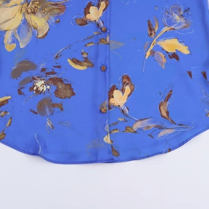 Dettaglio ravvicinato della camicia in raso blu con stampa floreale e bottoni in resina