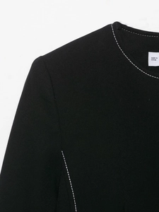 Detailed close-up of contrasting white stitching on the black blazer shoulder and collar