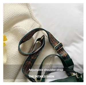 Detail of wide adjustable jacquard strap with gold metal buckle on dark green tote bag