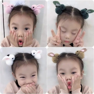 Detailed view of plush 3D bunny hair clips in various colors worn by a little girl