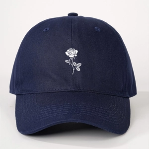 Detailed close-up of white rose embroidery on navy blue baseball cap fabric texture