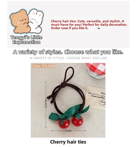 Detailed view of cherry hair ties with red pendants and green satin leaves on cream fabric