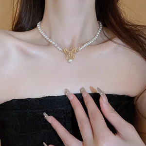 Collier ras du cou élégant avec papillon doré ajouré et perles blanches sur modèle
