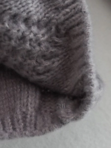 Dettaglio macro della trama a maglia con motivo a rombi del maglione grigio in lana