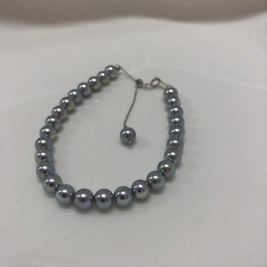 Detailed top view of s925 silver pearl bracelet with peacock green luster and gold clasp