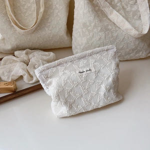 Detailed close-up of beige lace floral embroidery and simple wish label on cotton bag