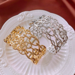 Detail view of gold and silver hollow pig nose chain bracelets on a textured plate