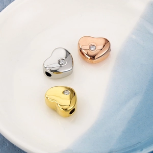 Vue détaillée de perles en forme de cœur en acier inoxydable et strass dorés et argentés