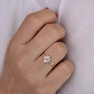 Macro shot of luxury gold flower ring with marquise cut diamonds on finger