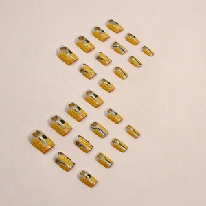 Yellow corn textured press-on nails with green leaves and gold glitter heart accents