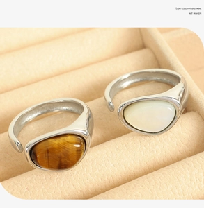 Close-up of vintage tiger eye and white stone open rings in a beige jewelry tray