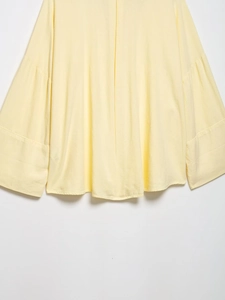 Detailed macro view of the lemon yellow linen shirt hem with soft cotton textures