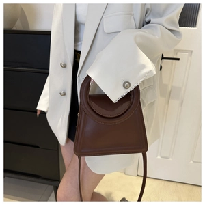 Detail view of a brown faux leather mini tote bag with a unique circular cutout handle