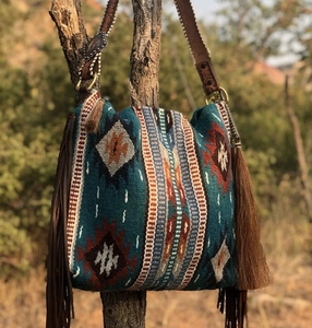 Detail of bohemian woven hobo bag with fringe and geometric patterns on a tree branch