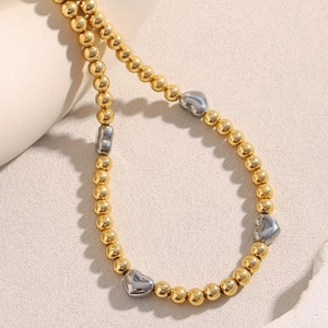 Dettaglio della collana di perline placcata oro 18K con ciondoli a cuore in argento